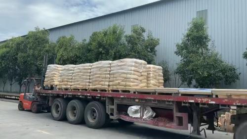 車間內(nei) 工人正在將粉狀聚丙烯酰胺裝車的場景，展示裝車過程中的操作細節